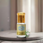 A premium glass vial of pure Mogra Absolute Oil by Sai Perfume, surrounded by freshly handpicked, tightly curled white Jasmine Sambac blossoms.